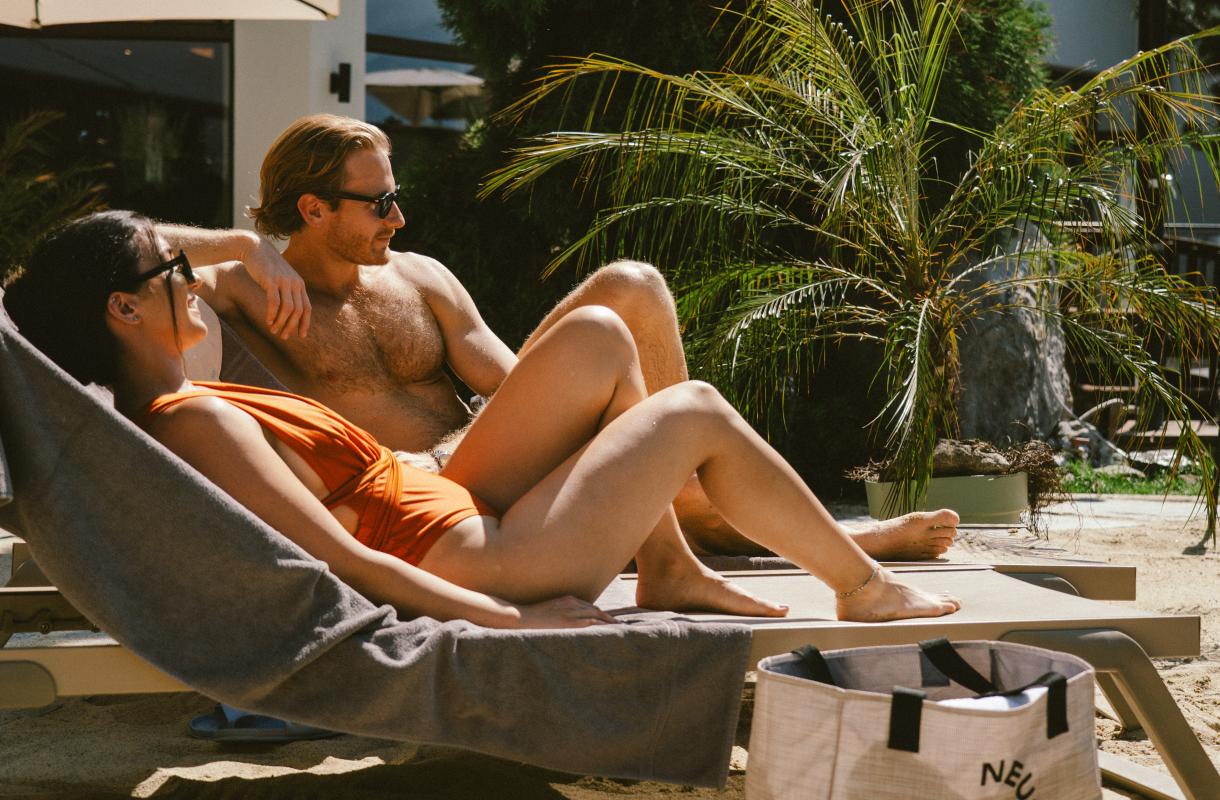 paar liegt am pool auf liegest&uuml;hlen
